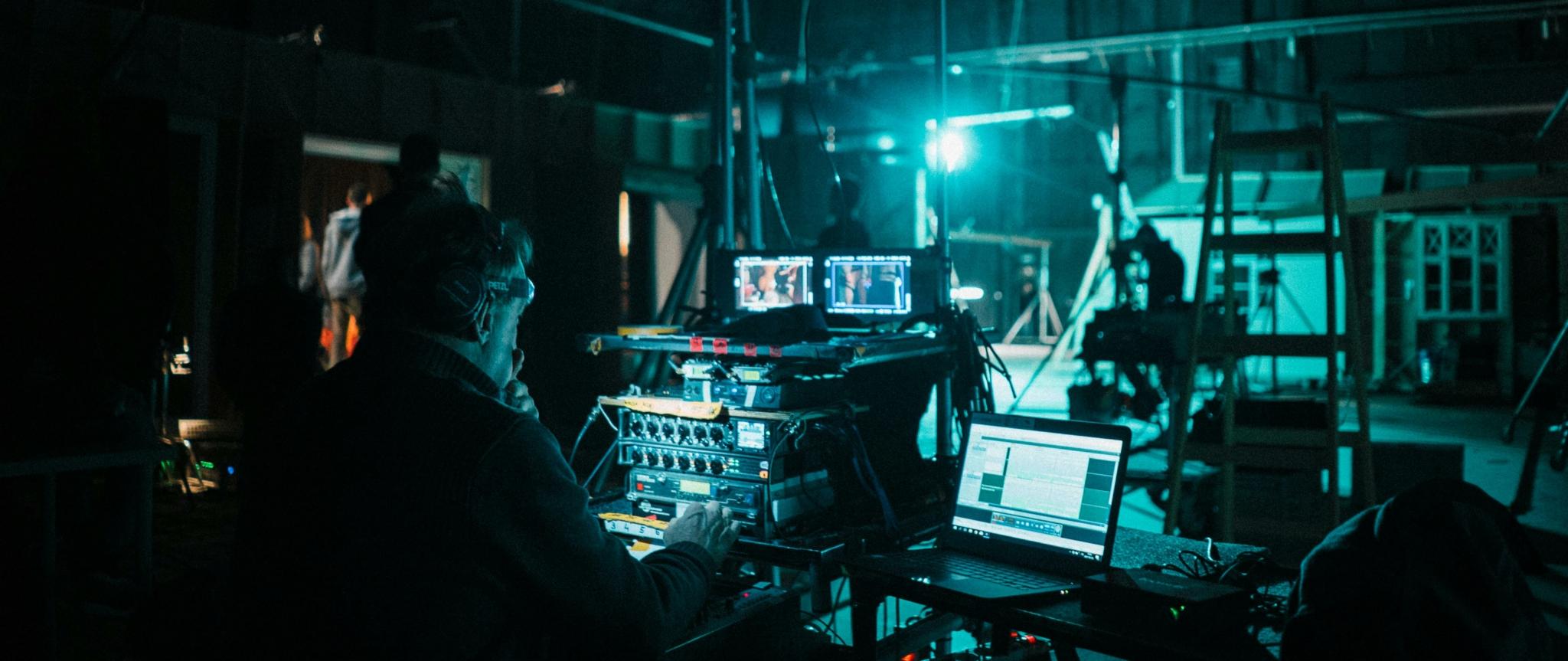 A sound engineer working on equipment in a dimly lit studio.