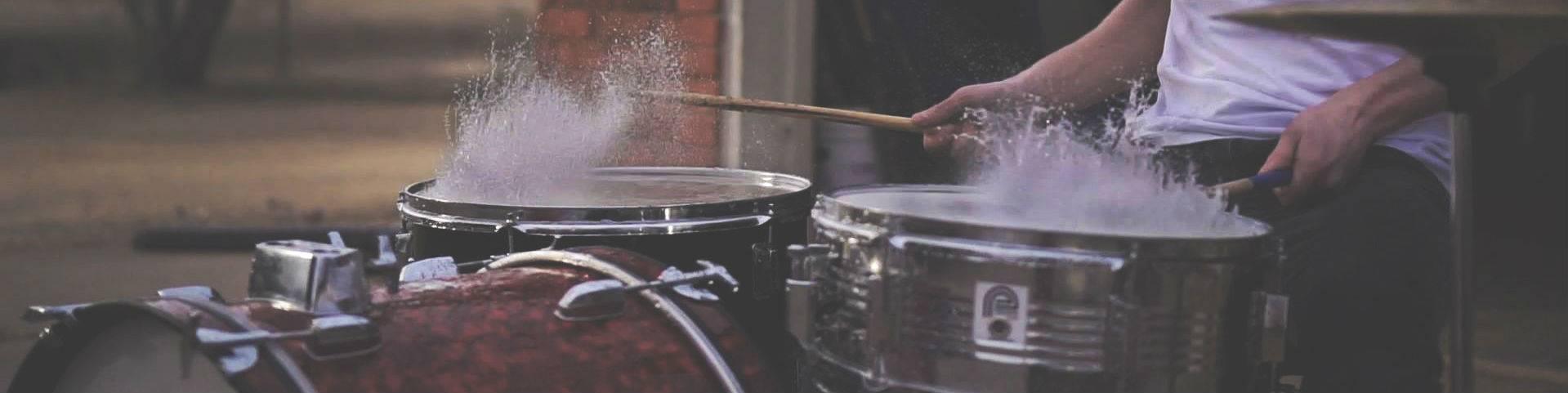 A drummer playing wet drums that are splashing