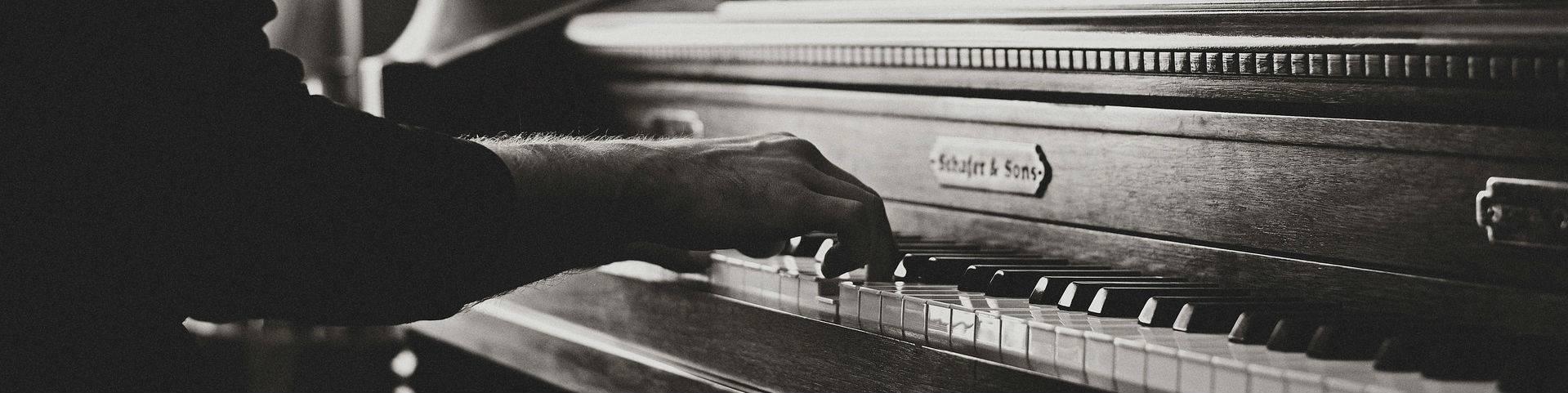 A black and white image of hands playing a piano