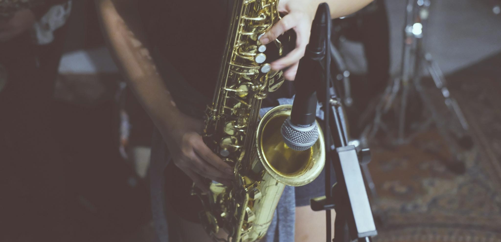 A musician playing a saxophone in a studio setting with a microphone