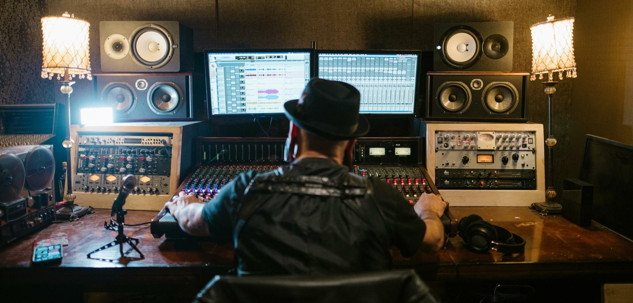 A music producer working in a recording studio with various audio equipment.