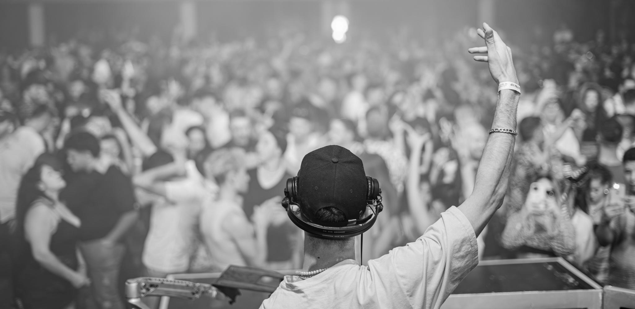 Black and white DJ seen from behind performing live for a crowd