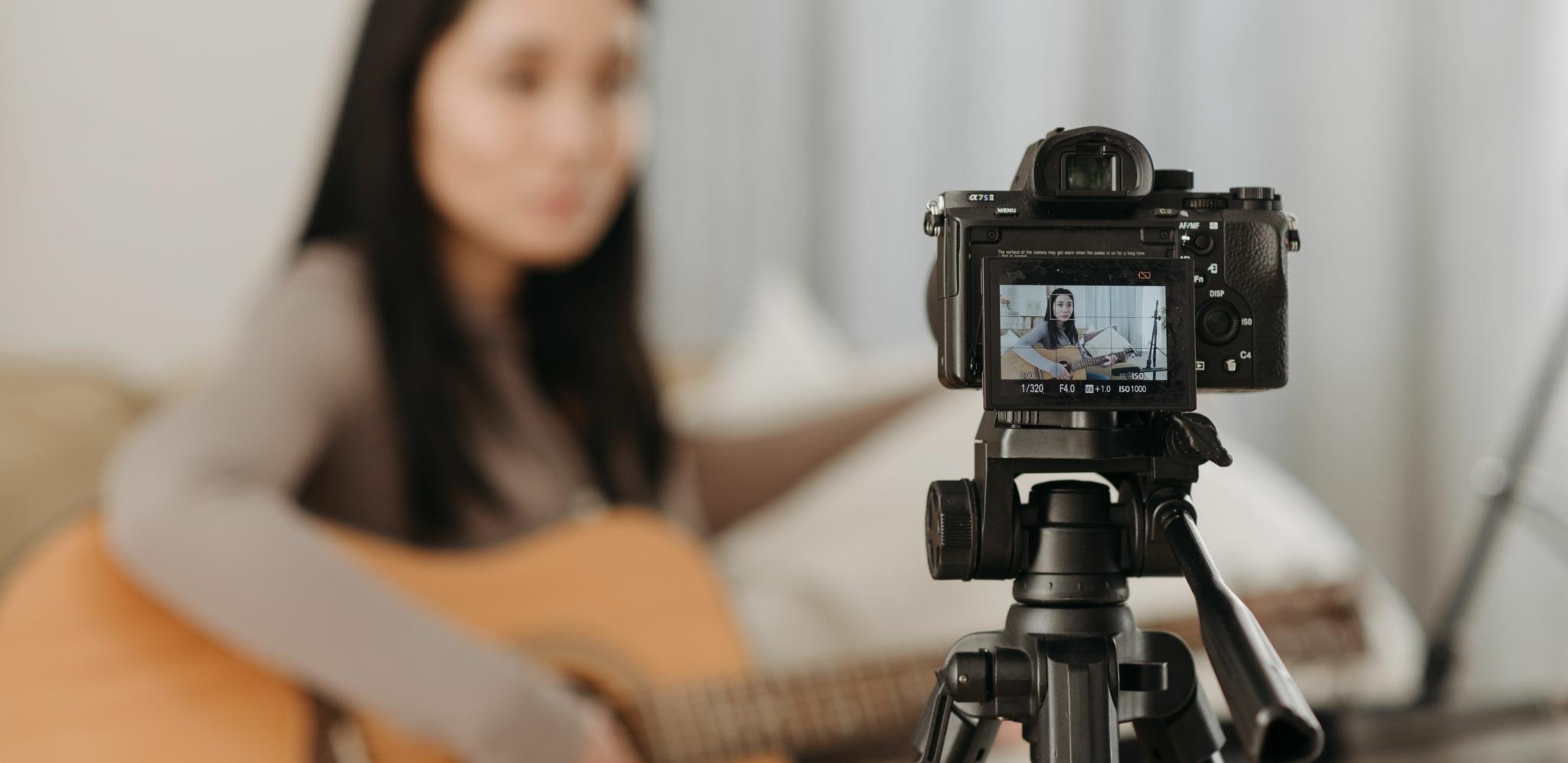 Sony mirrorless camera on a tripod filming a guitarist