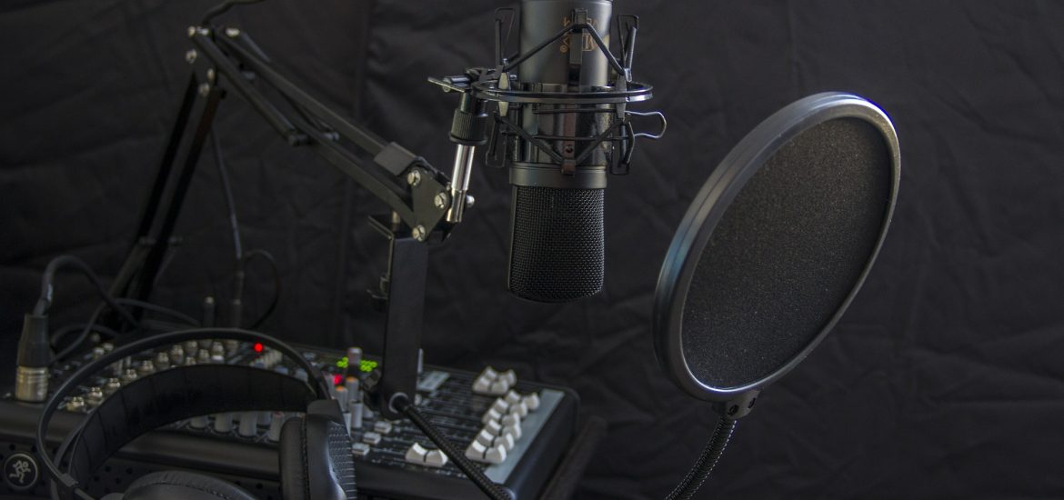 A podcast setup showing a mixer, microphone and headphones