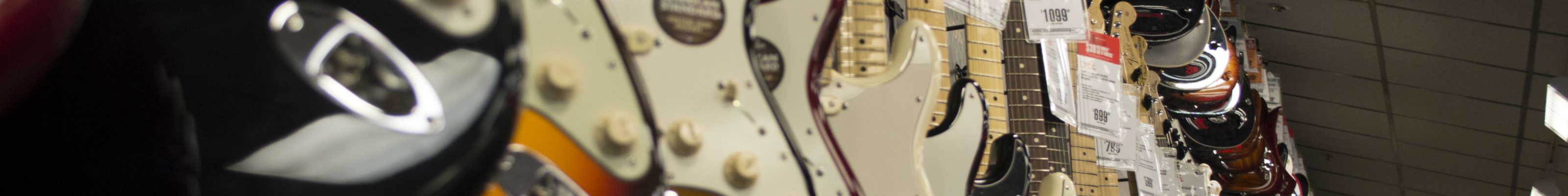 A lot of electric guitars hanging on a wall