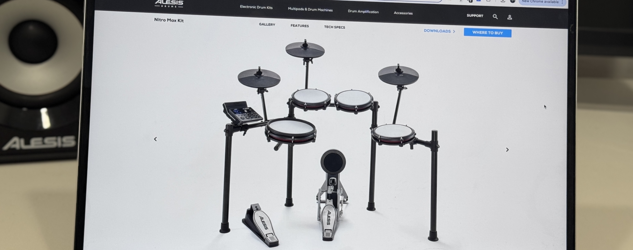Alesis Nitro Max electronic drum kit displayed on a computer screen with studio monitors in the background.