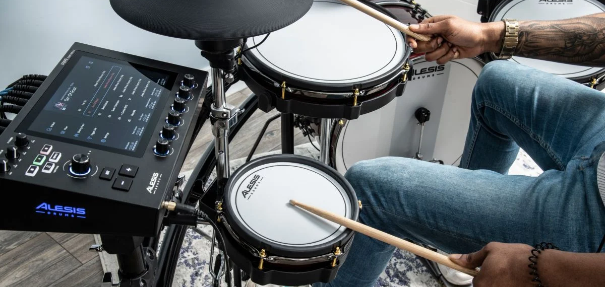 A person playing an Alesis electronic drum kit with a digital interface.