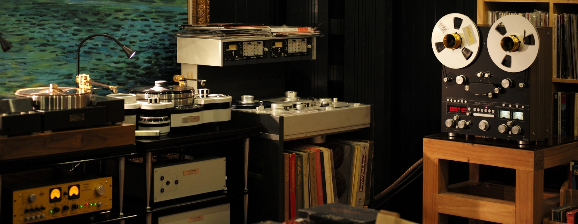 Audio production equipment setup with reel-to-reel tape recorder and turntables.
