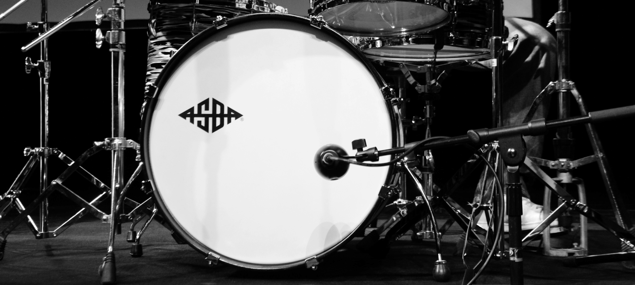 Close-up of a drum kit featuring a bass drum and snare, with microphones positioned for recording.