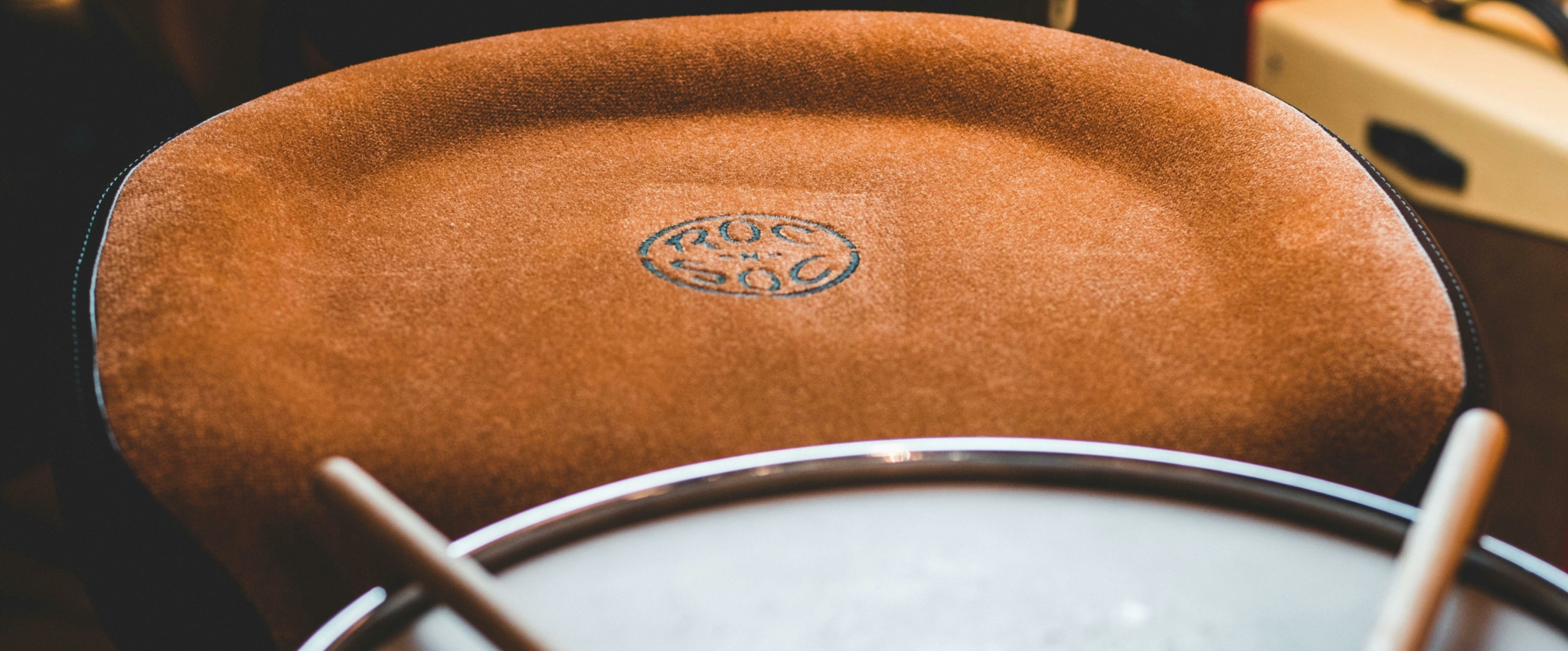 Close-up of a drum seat and snare drum with sticks, showcasing the texture and design of the seat.