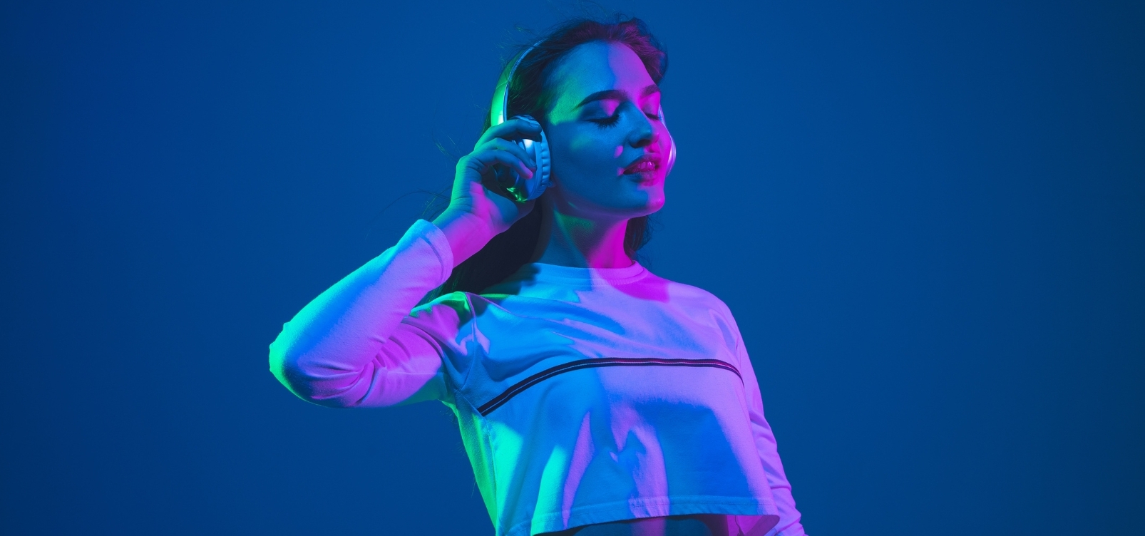 Young woman enjoying music with headphones in a colorful setting.