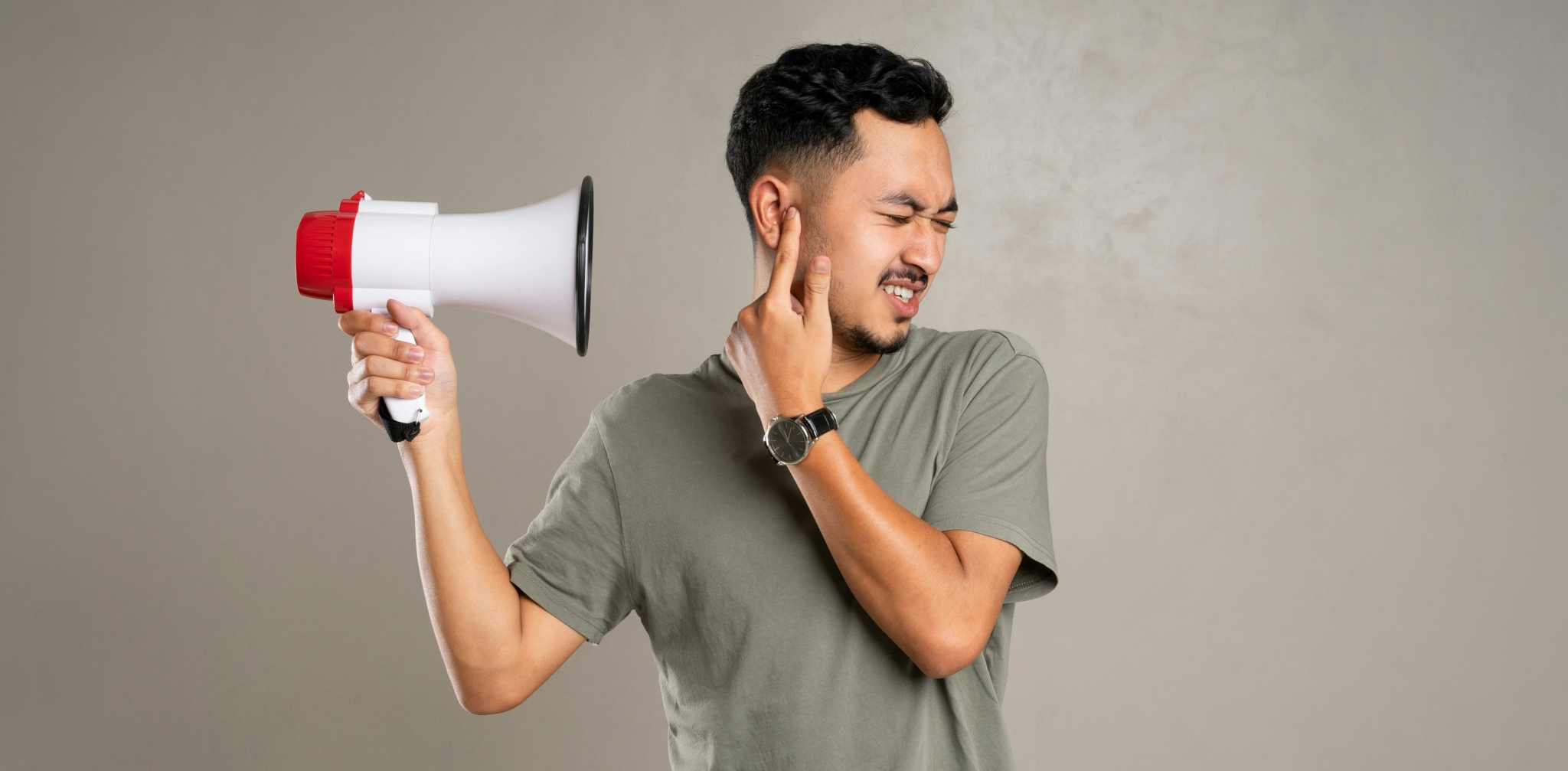 A person holding a megaphone to their ear, showing a reaction to loud noise.