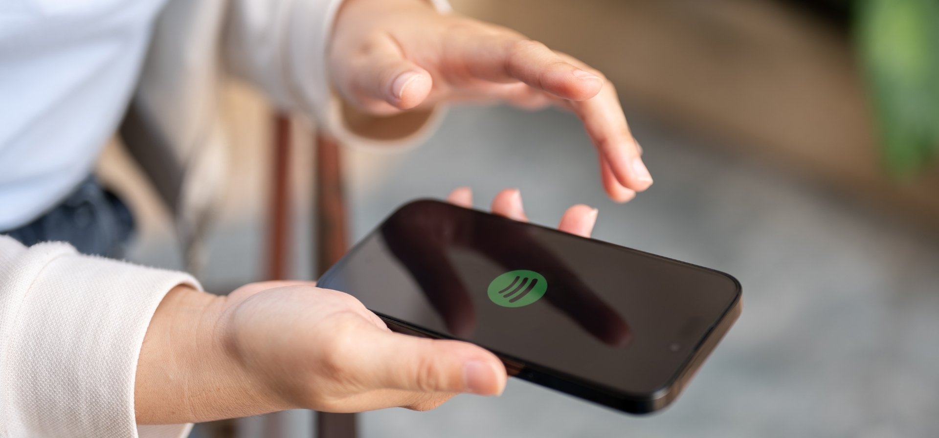 A person holding a smartphone with the Spotify logo displayed on the screen.