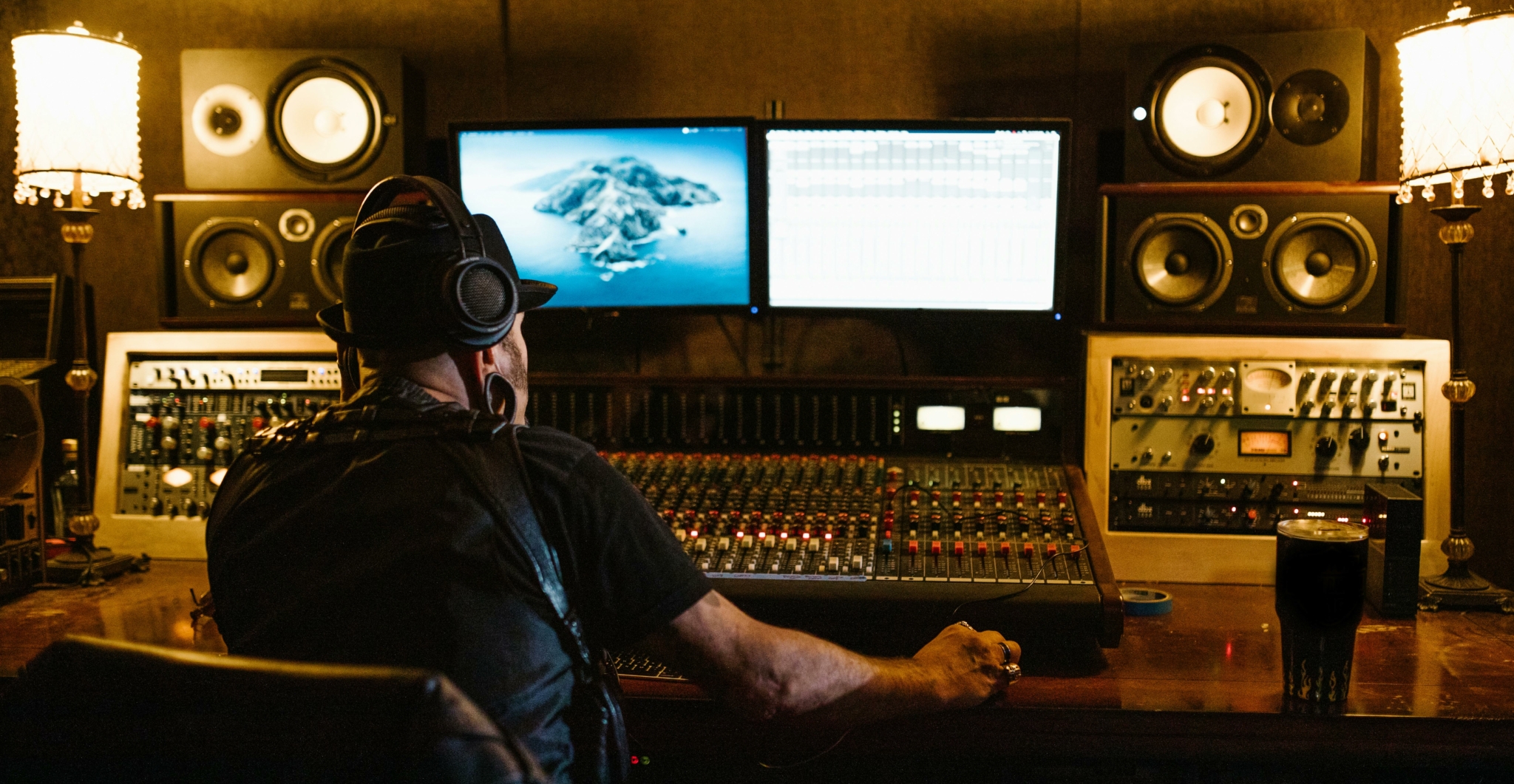 A music producer working in a recording studio with audio equipment and dual monitors after recording live performance