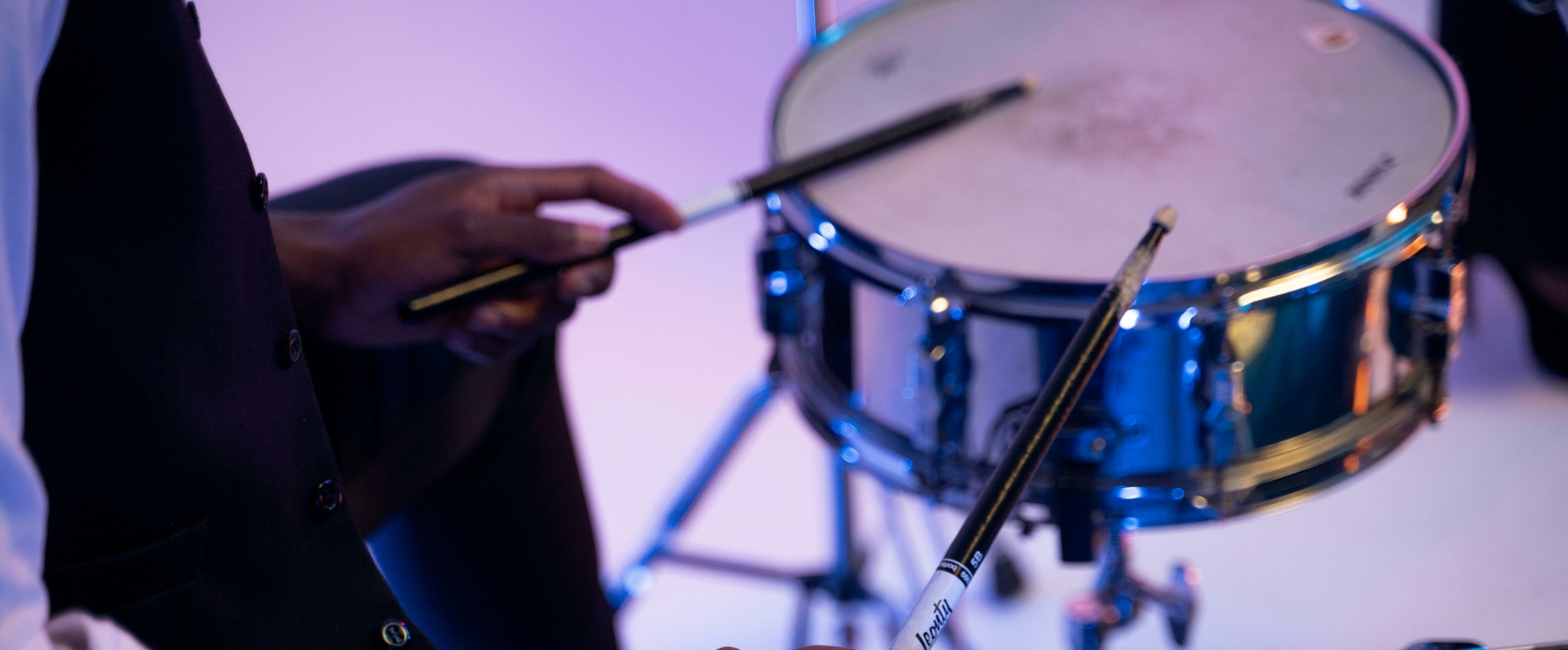 A drummer holding drumsticks over a snare drum in a creative setting.