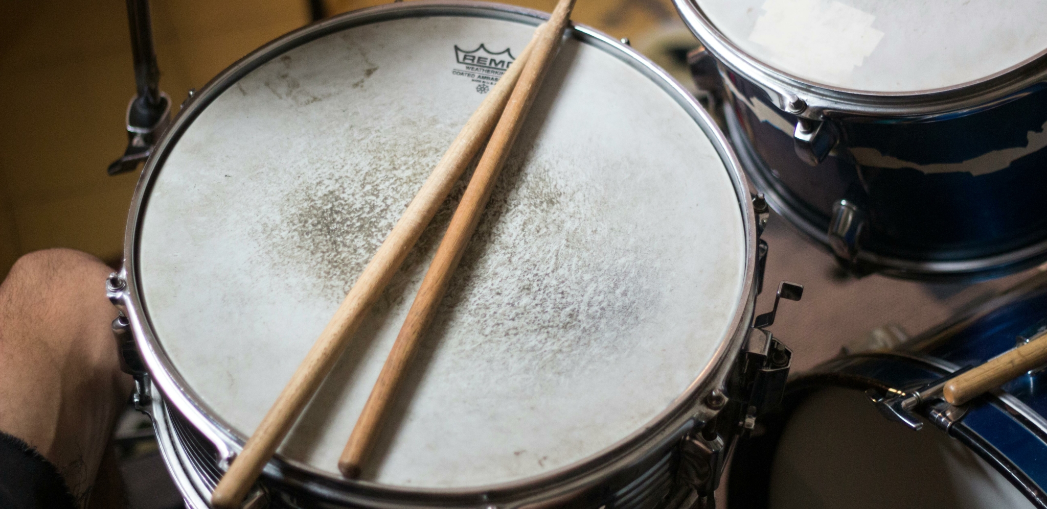 Close-up of a drum set with drumsticks resting on the snare drum.