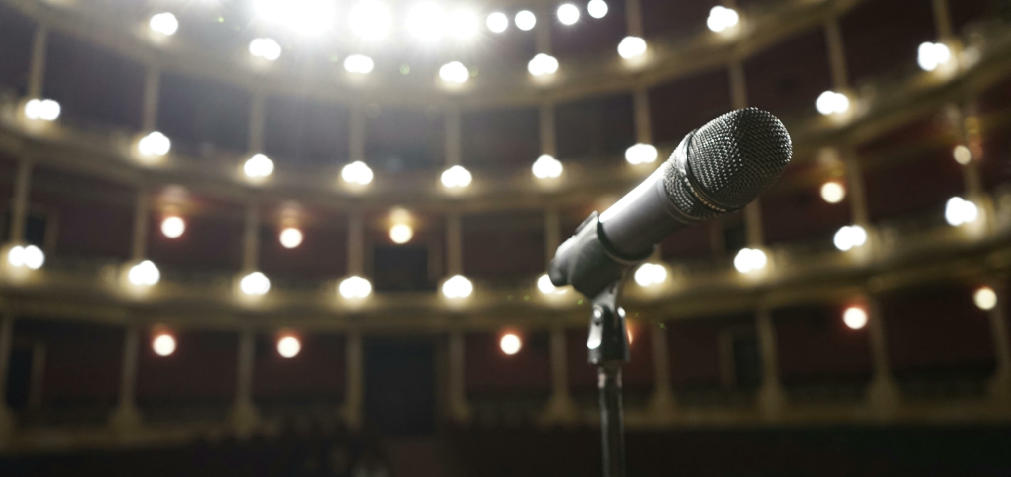 Close-up view of a microphone on a stand with a theater background.