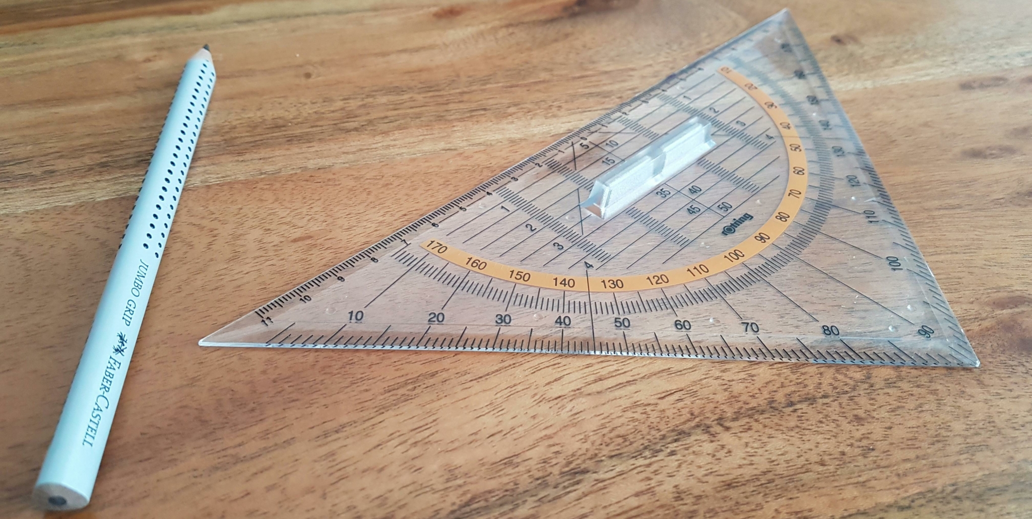A clear triangular protractor and a pencil on a wooden surface.