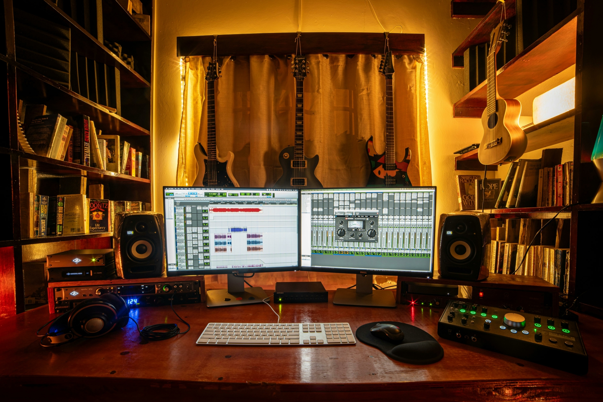 Espacio de producción de audio bien equipado con monitores, una interfaz DAW y diversos instrumentos.