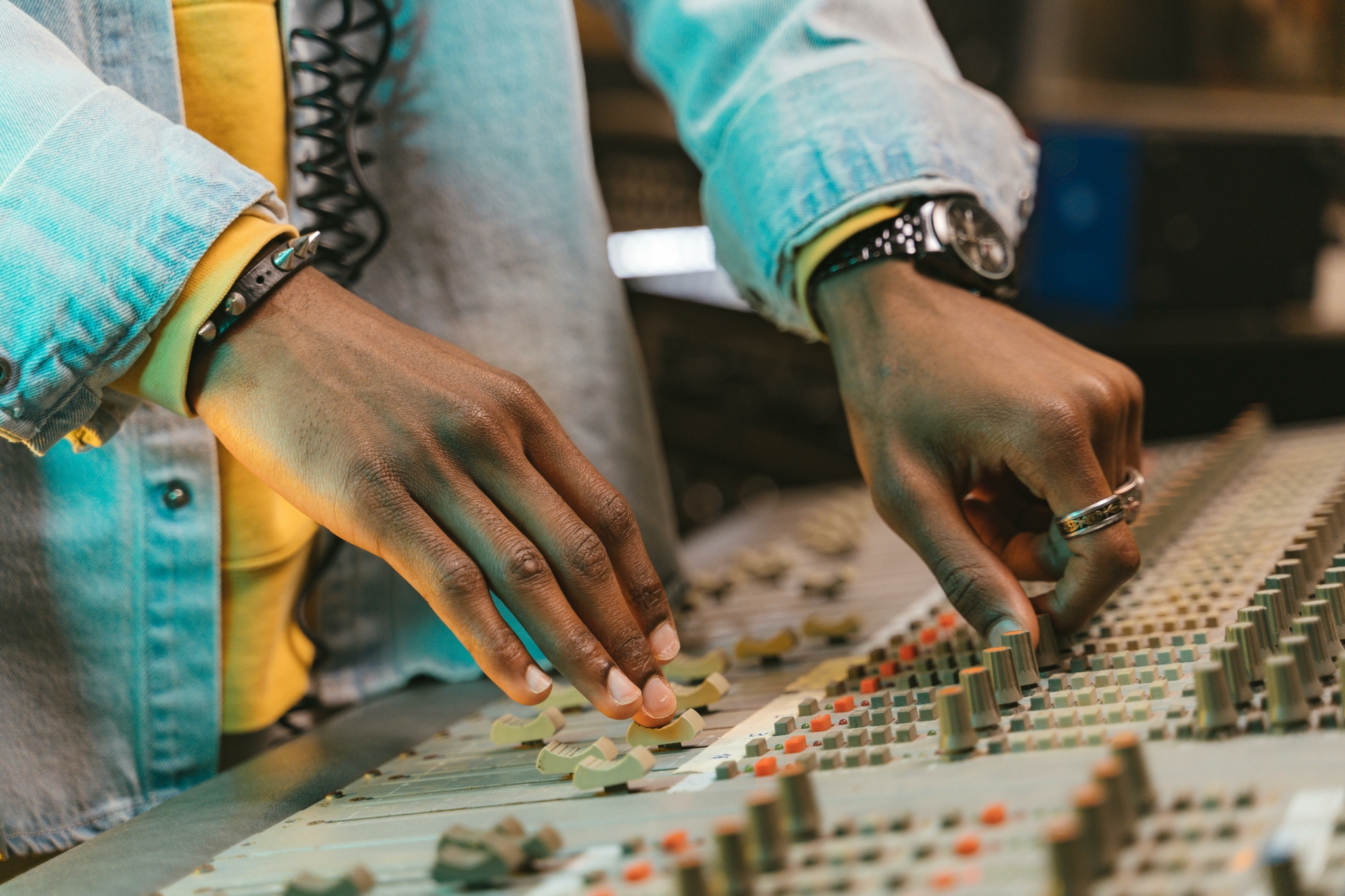Primer plano de una persona ajustando los controles de una mesa de mezclas de audio