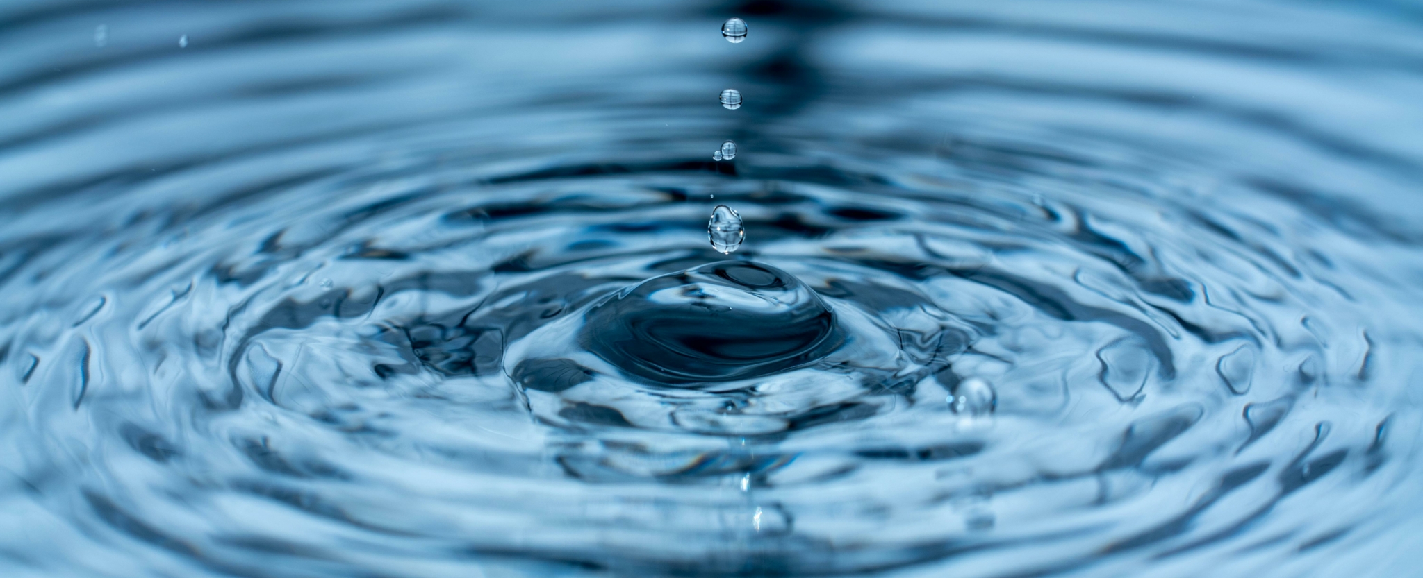 Close-up image of water droplets creating ripples on a surface.