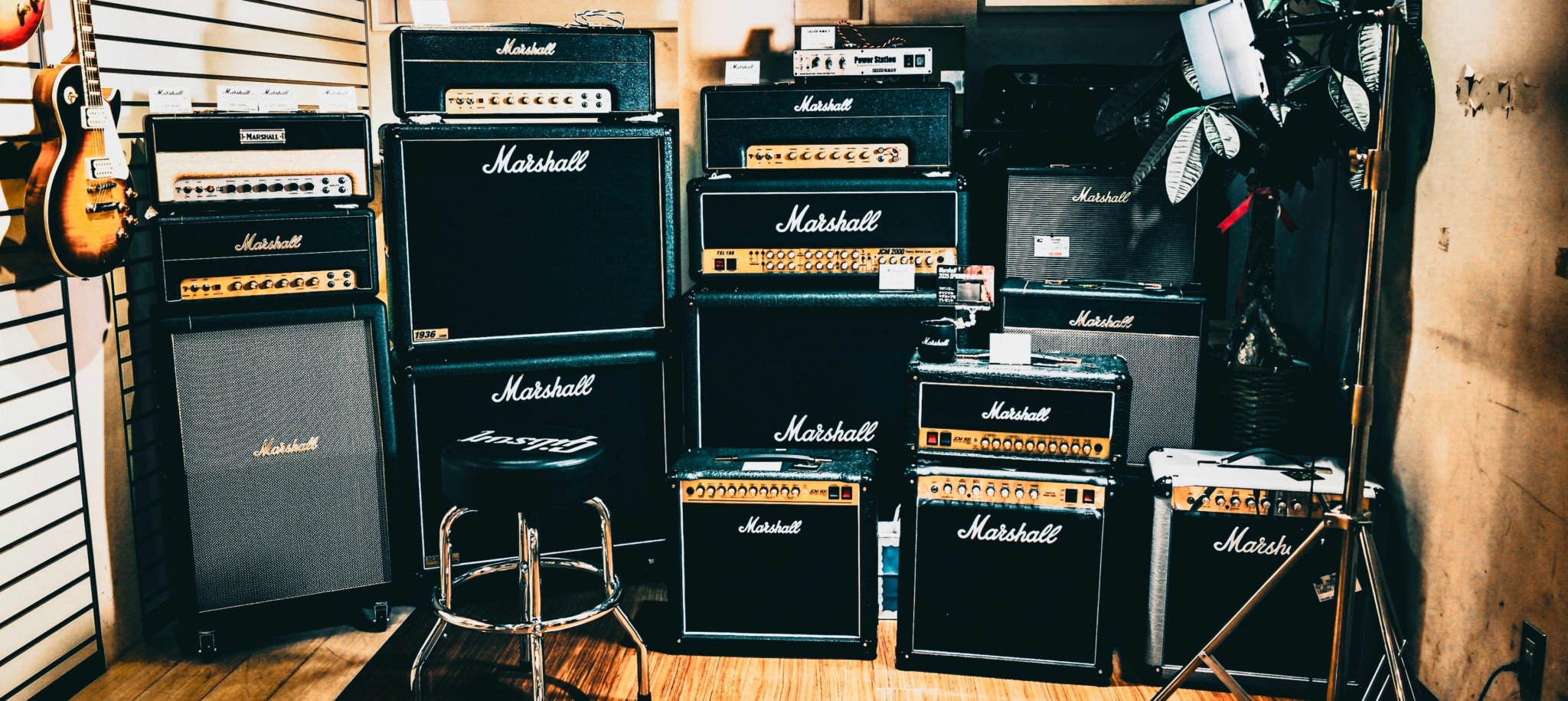 Marshall guitar amplifiers and speaker cabinets displayed with an electric guitar in a music store