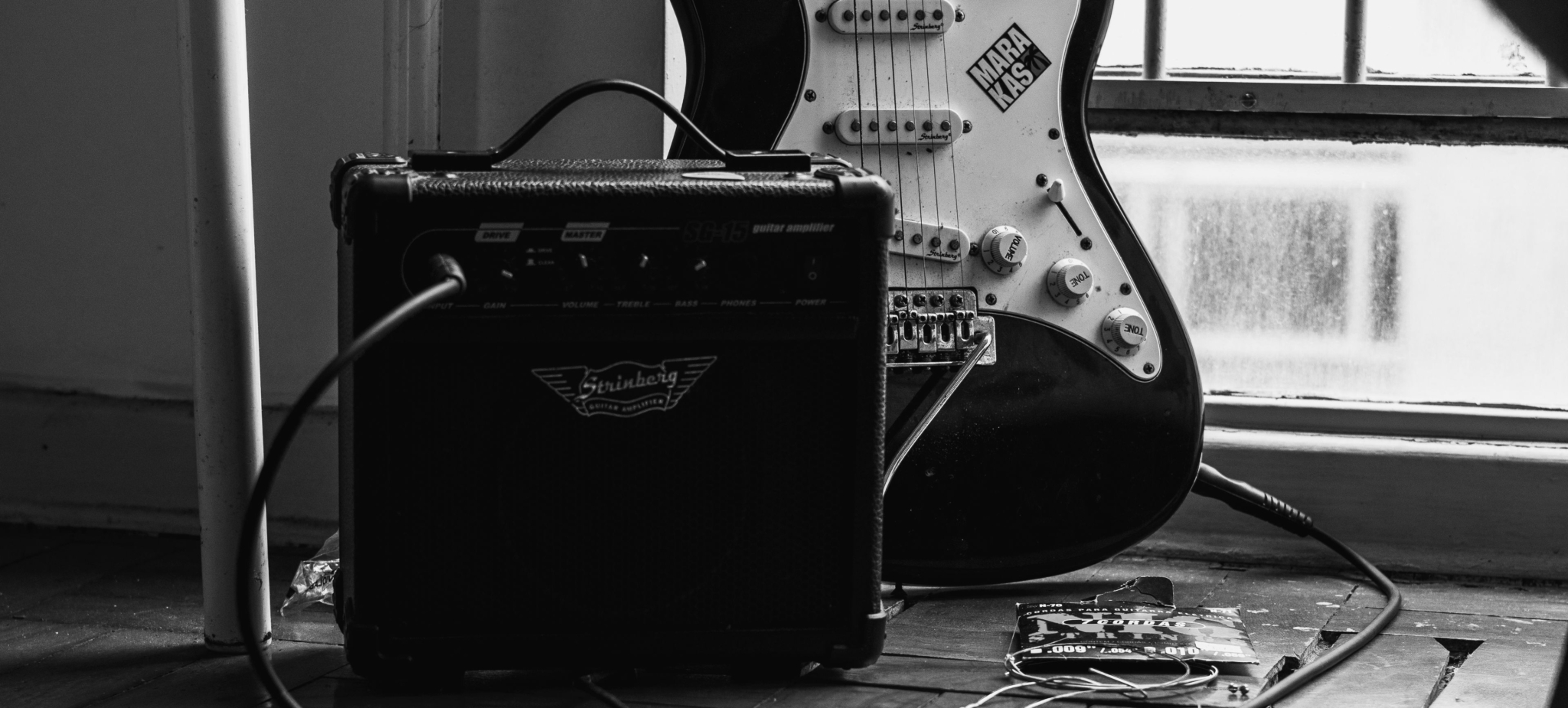 Black-and-white electric guitar with Strinberg amplifier and cables